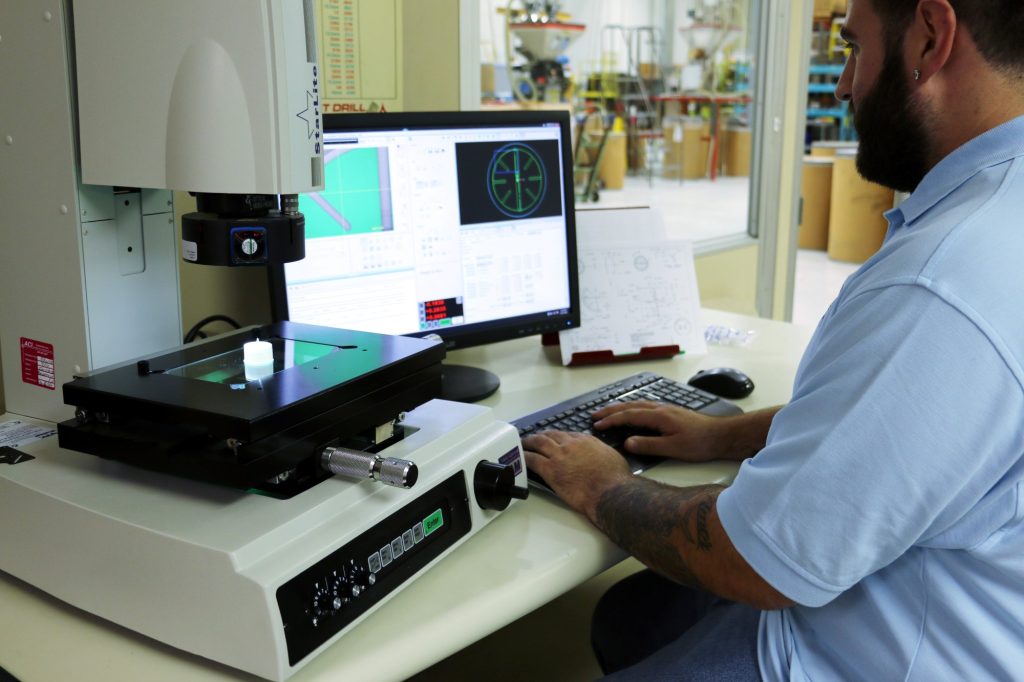 Midstate Mold employee scans manufactured plastic part for defects in QA process.