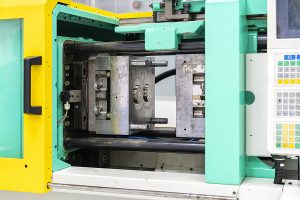 Closeup of the inside of an injection molding machine, showing an open injection mold and surrounding press.