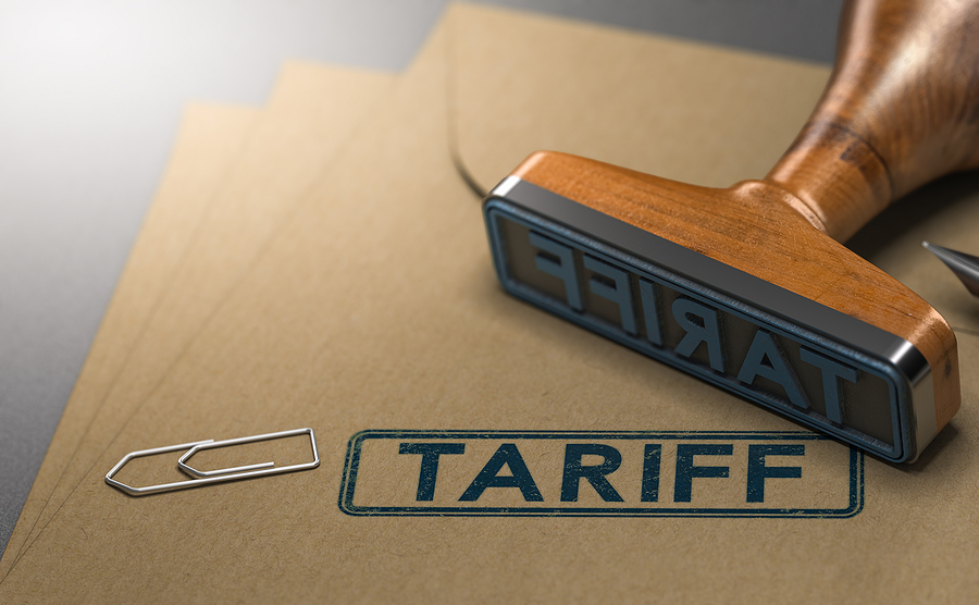 Image of a stamp marking "tariff" on a document with business supplies nearby.